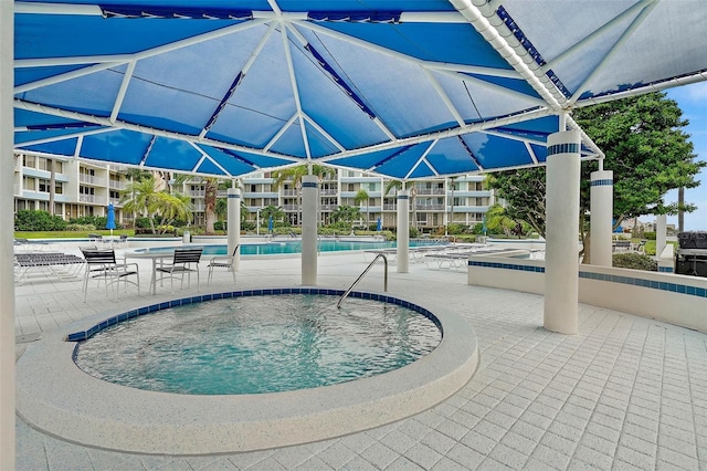 view of swimming pool featuring a hot tub and a patio