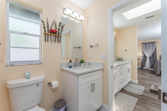 bathroom with vanity, hardwood / wood-style floors, a skylight, and toilet