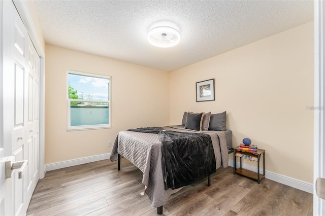 bedroom featuring a textured ceiling, light wood-type flooring, and a closet