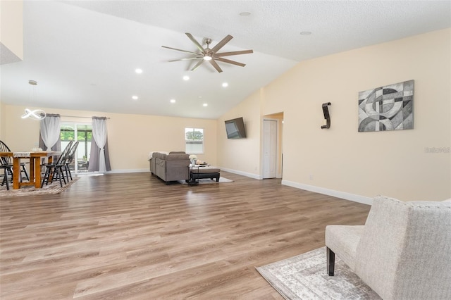 living room featuring vaulted ceiling, a textured ceiling, and light wood-type flooring