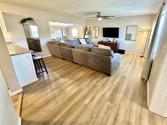 living room with ceiling fan, light hardwood / wood-style floors, and a textured ceiling