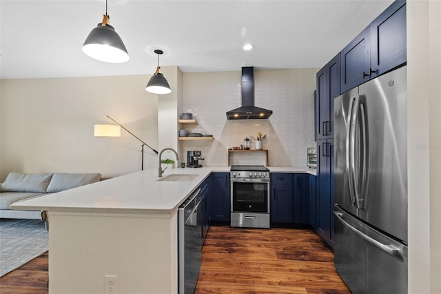 kitchen with sink, hanging light fixtures, appliances with stainless steel finishes, kitchen peninsula, and wall chimney range hood