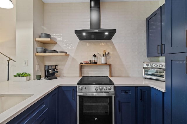 kitchen with stainless steel range with electric stovetop, wall chimney exhaust hood, and blue cabinets