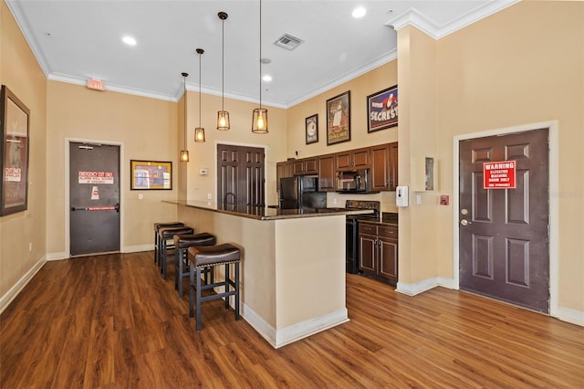 kitchen with a breakfast bar, decorative light fixtures, black appliances, dark hardwood / wood-style flooring, and kitchen peninsula