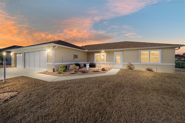 ranch-style home featuring a garage and a lawn