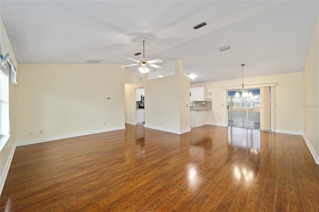 unfurnished living room with ceiling fan with notable chandelier, dark hardwood / wood-style flooring, and vaulted ceiling