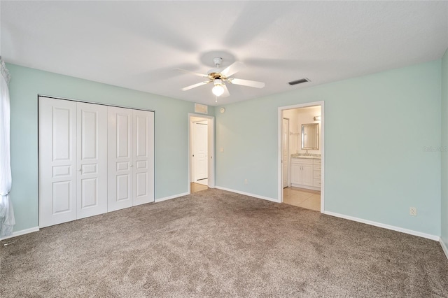 unfurnished bedroom with ceiling fan, a closet, ensuite bathroom, and light carpet