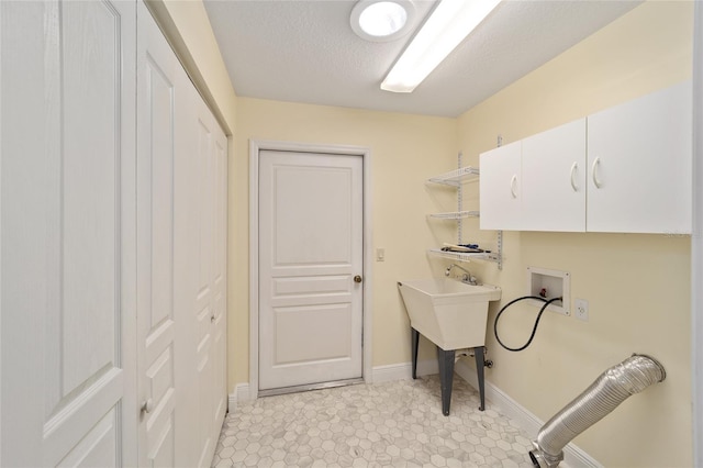 laundry room with hookup for a washing machine, cabinets, and a textured ceiling