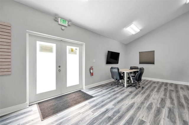 home office featuring vaulted ceiling, light wood-type flooring, and french doors