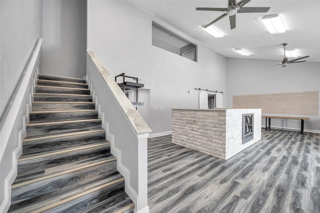 staircase with ceiling fan, lofted ceiling, and hardwood / wood-style floors