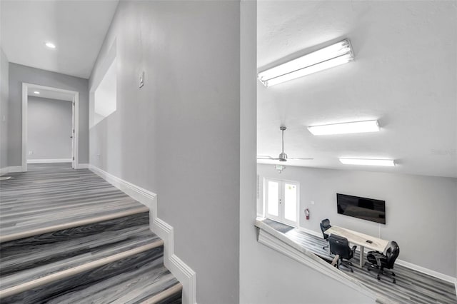 staircase featuring wood-type flooring and ceiling fan