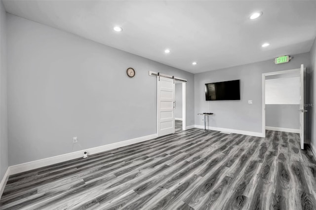 unfurnished living room featuring wood-type flooring and a barn door