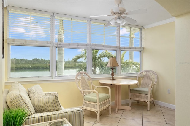 sunroom with ceiling fan and a water view