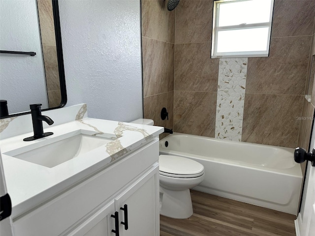 full bathroom with vanity, hardwood / wood-style floors, toilet, and tiled shower / bath