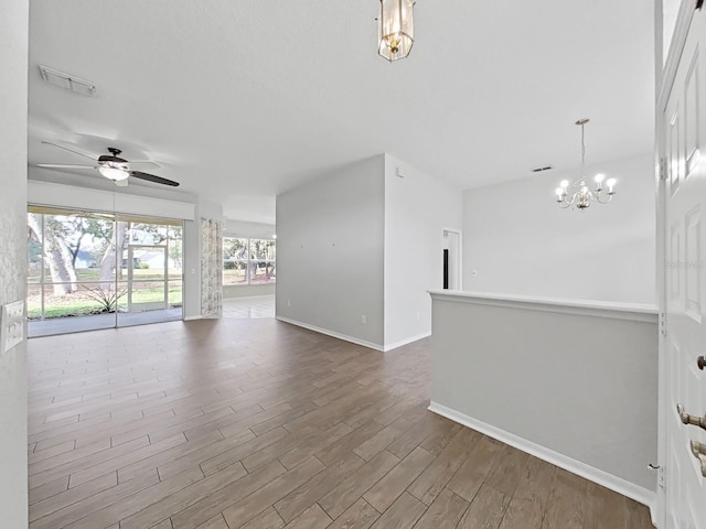 spare room featuring hardwood / wood-style flooring and ceiling fan with notable chandelier