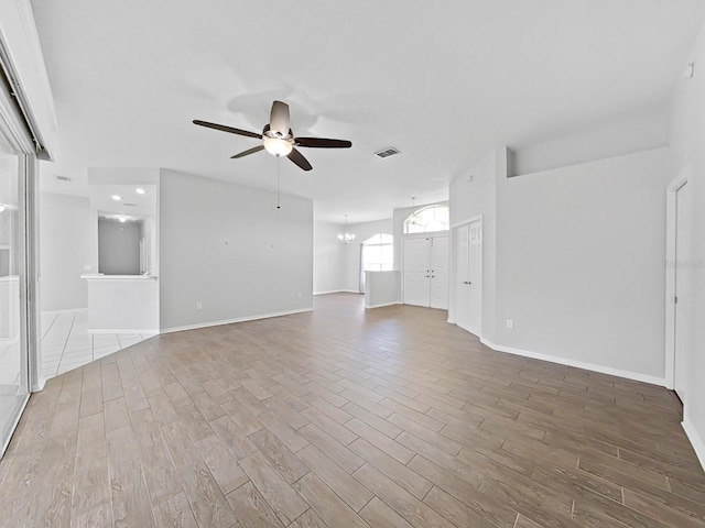 unfurnished living room featuring ceiling fan with notable chandelier and hardwood / wood-style floors