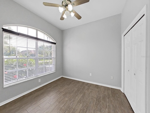unfurnished bedroom with a closet, dark hardwood / wood-style floors, and ceiling fan