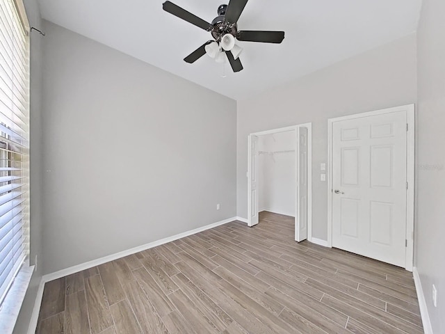 unfurnished bedroom featuring ceiling fan, multiple windows, light hardwood / wood-style floors, and a closet