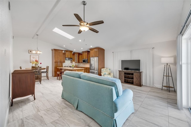 living room featuring sink, vaulted ceiling with skylight, and ceiling fan