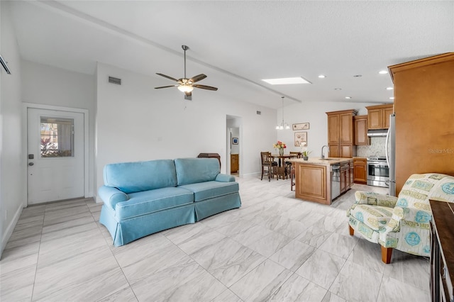 living room with ceiling fan, lofted ceiling with skylight, and sink