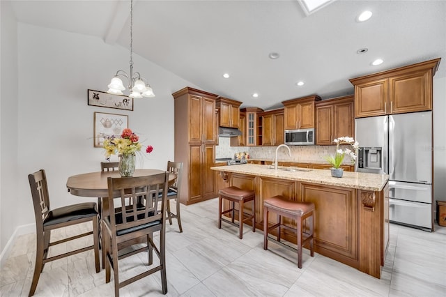 kitchen featuring pendant lighting, sink, a kitchen island with sink, light stone counters, and stainless steel appliances