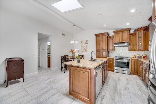 kitchen featuring sink, range hood, stainless steel appliances, light stone counters, and an island with sink