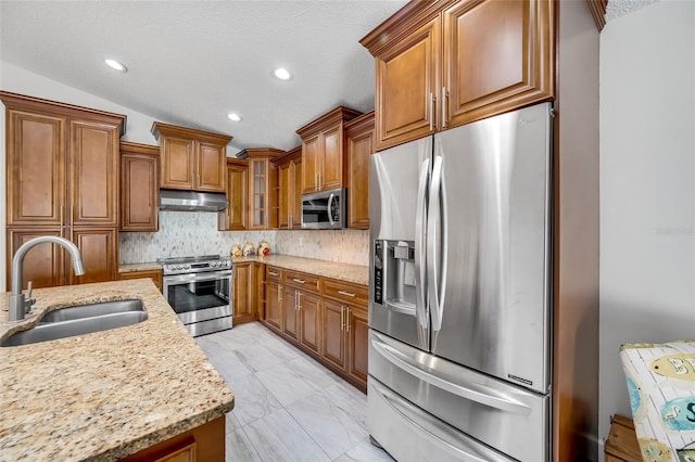 kitchen featuring sink, appliances with stainless steel finishes, tasteful backsplash, light stone countertops, and a textured ceiling