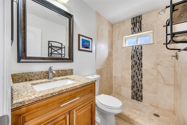 bathroom with vanity, toilet, and tiled shower