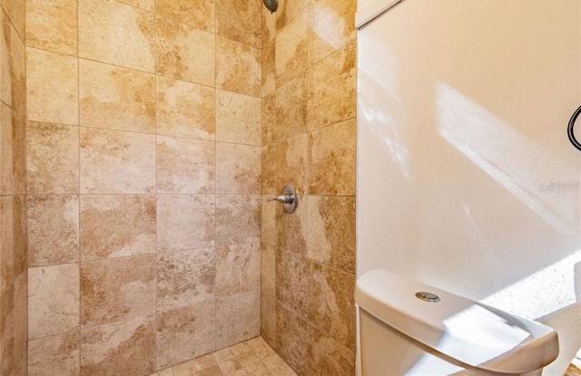 bathroom featuring tiled shower and toilet