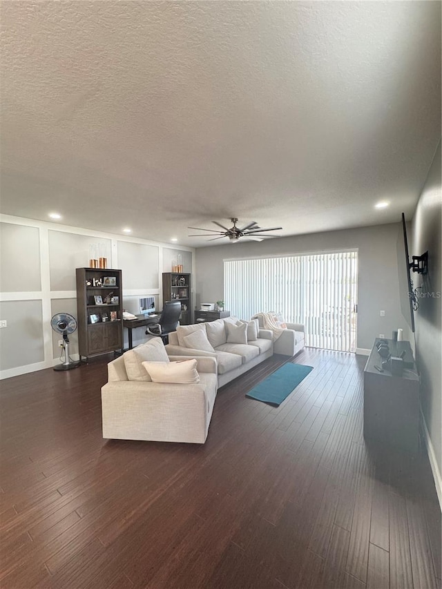 living room featuring dark hardwood / wood-style flooring, ceiling fan, and a textured ceiling