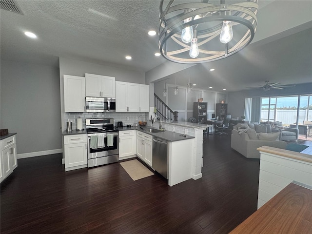 kitchen featuring hanging light fixtures, appliances with stainless steel finishes, white cabinets, and kitchen peninsula