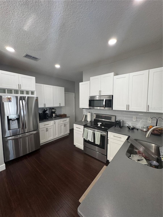 kitchen featuring sink, dark hardwood / wood-style floors, white cabinets, and appliances with stainless steel finishes