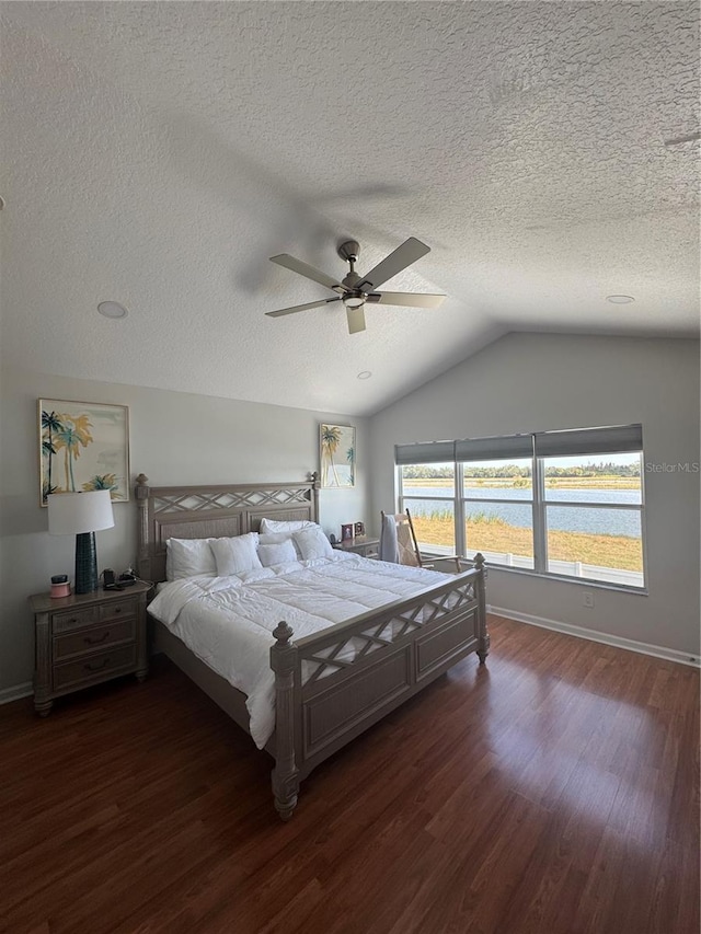 bedroom featuring lofted ceiling, dark hardwood / wood-style floors, ceiling fan, and a water view