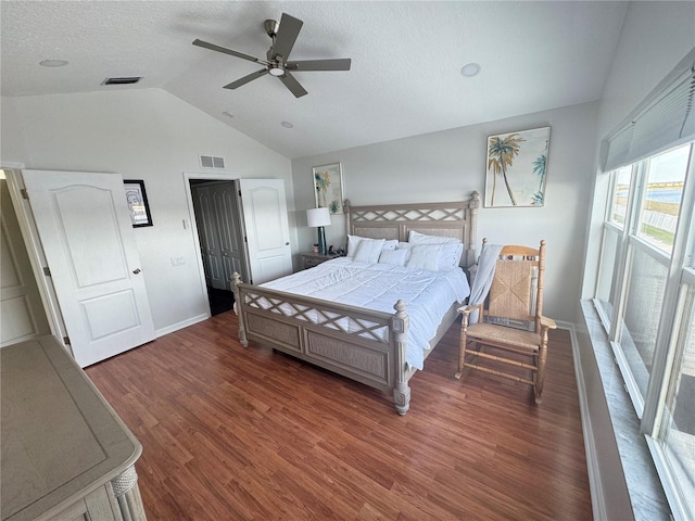 bedroom with lofted ceiling, a textured ceiling, dark hardwood / wood-style floors, and ceiling fan