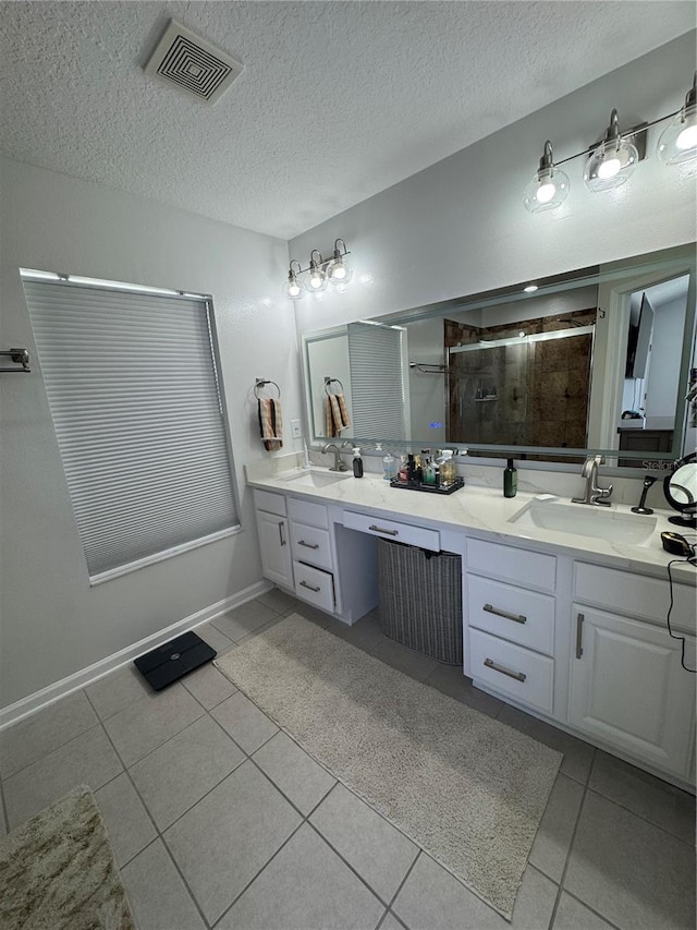 bathroom featuring tile patterned flooring, vanity, a textured ceiling, and a shower with shower door