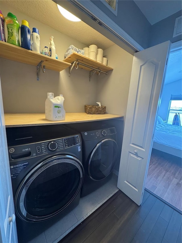 clothes washing area featuring dark wood-type flooring, washer and clothes dryer, and a textured ceiling