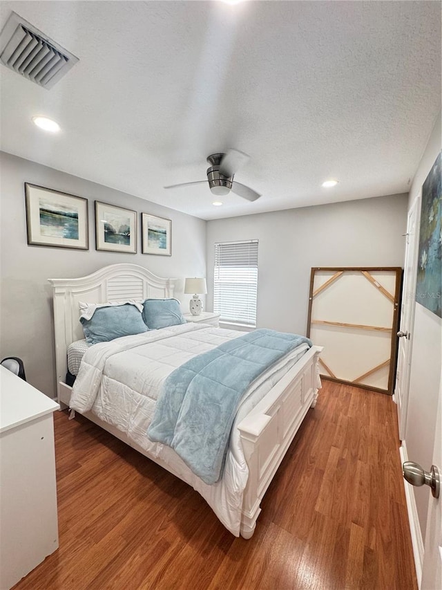 bedroom with hardwood / wood-style flooring, ceiling fan, and a textured ceiling