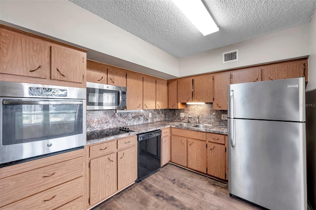 kitchen with sink, a textured ceiling, light wood-type flooring, decorative backsplash, and black appliances