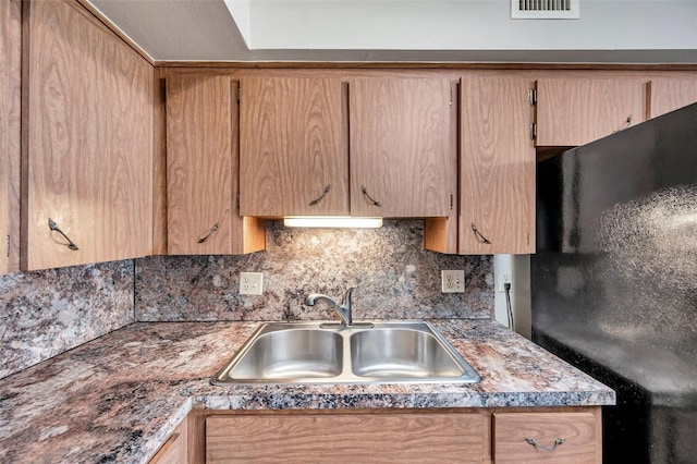 kitchen featuring tasteful backsplash, black refrigerator, and sink