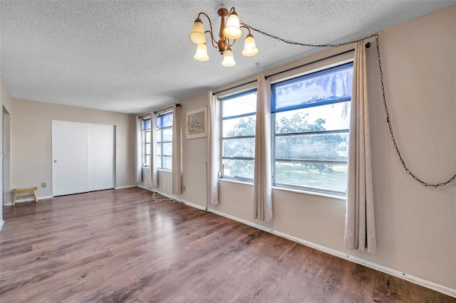 spare room with hardwood / wood-style floors, a textured ceiling, and a chandelier