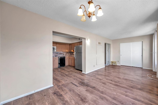 interior space with dark hardwood / wood-style floors, decorative backsplash, a notable chandelier, stainless steel appliances, and a textured ceiling