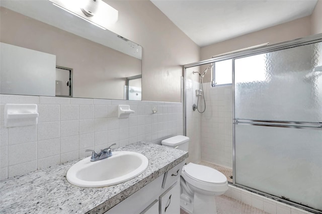 bathroom with tile walls, an enclosed shower, vanity, and toilet