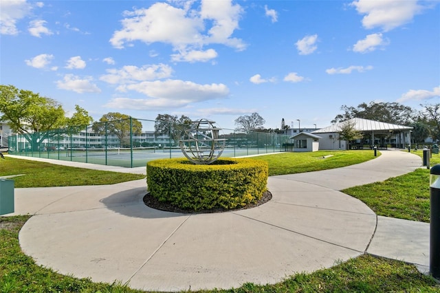 view of home's community featuring tennis court and a lawn