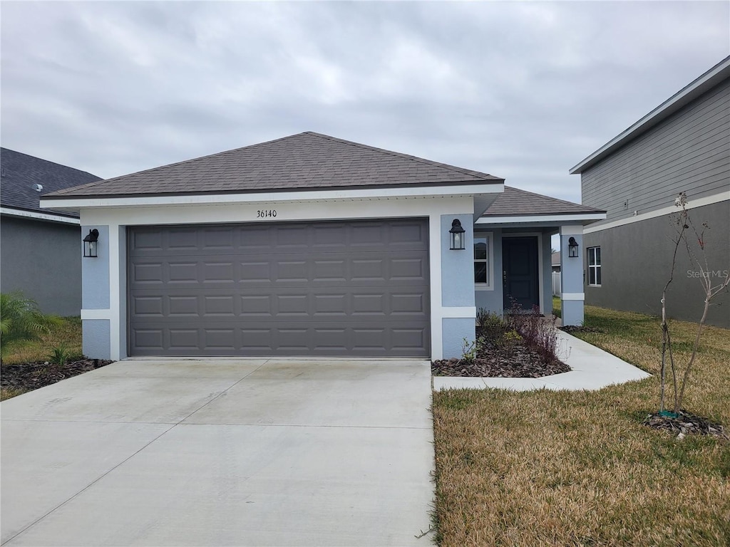 single story home with a garage and a front lawn