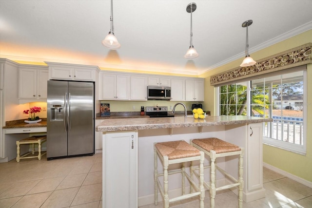 kitchen with stainless steel appliances, hanging light fixtures, a center island with sink, and white cabinets