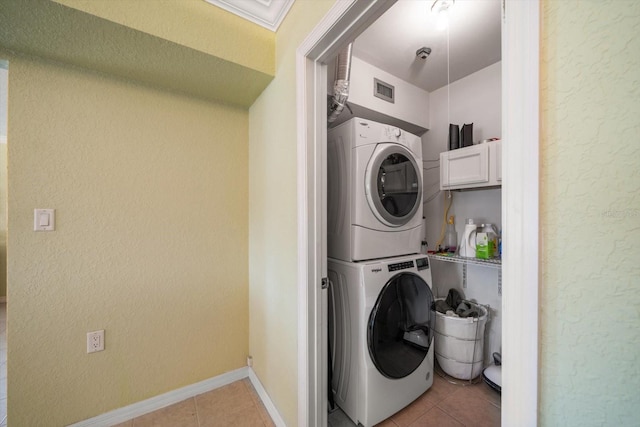 laundry room with light tile patterned floors and stacked washer / dryer