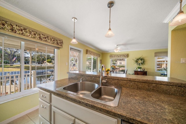 kitchen featuring sink, crown molding, hanging light fixtures, and light tile patterned flooring