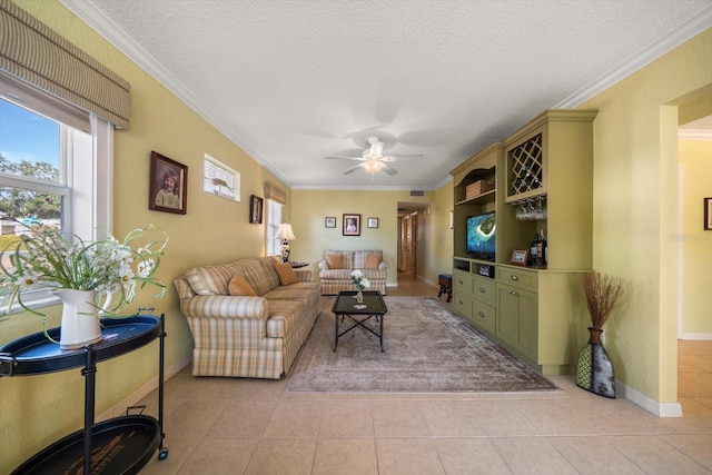 living room featuring crown molding, ceiling fan, a textured ceiling, and light tile patterned floors