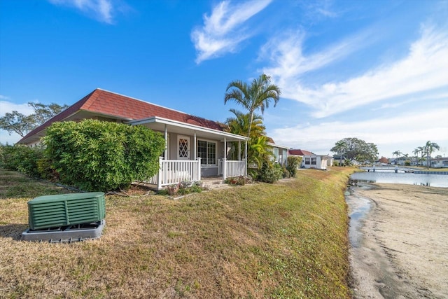 view of front facade with covered porch, a front lawn, and a water view