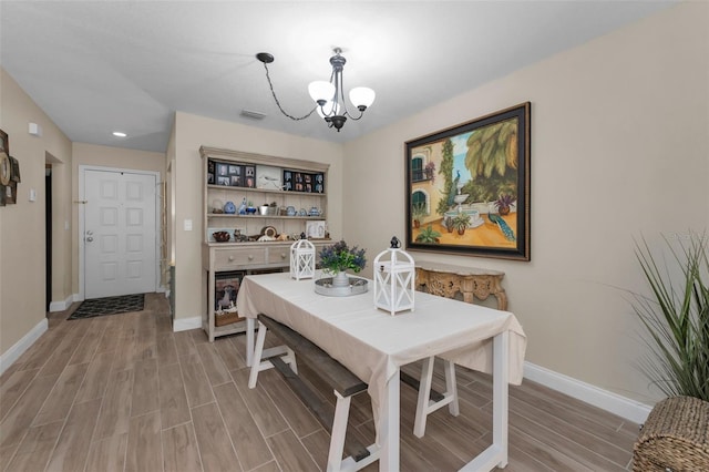 dining room with a chandelier, wood tiled floor, visible vents, and baseboards